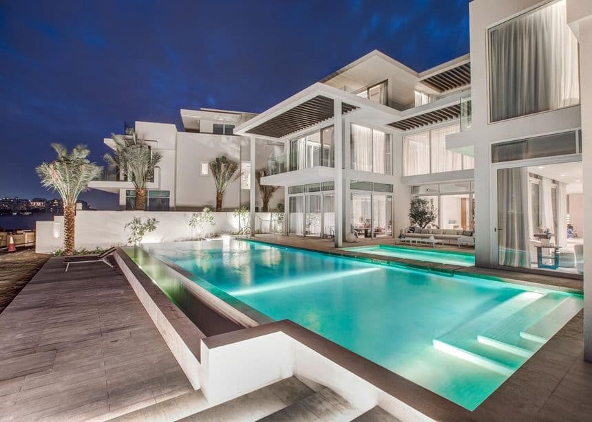A private villa in Dubai at dusk with the pool lit